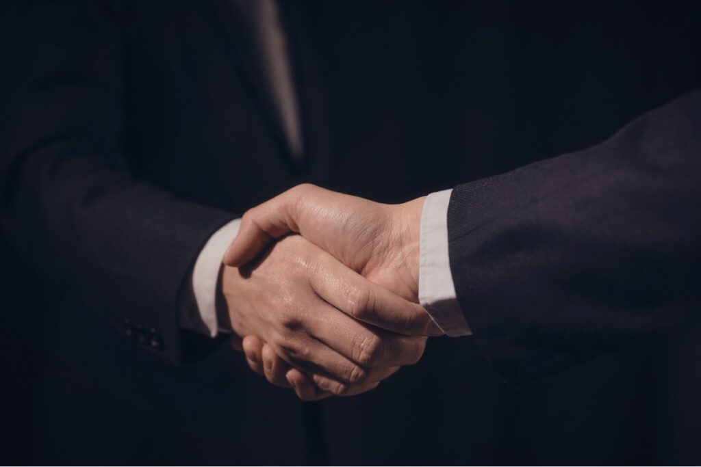 dos socios dándose un apretón de manos luego de firmar un pacto de accionistas
