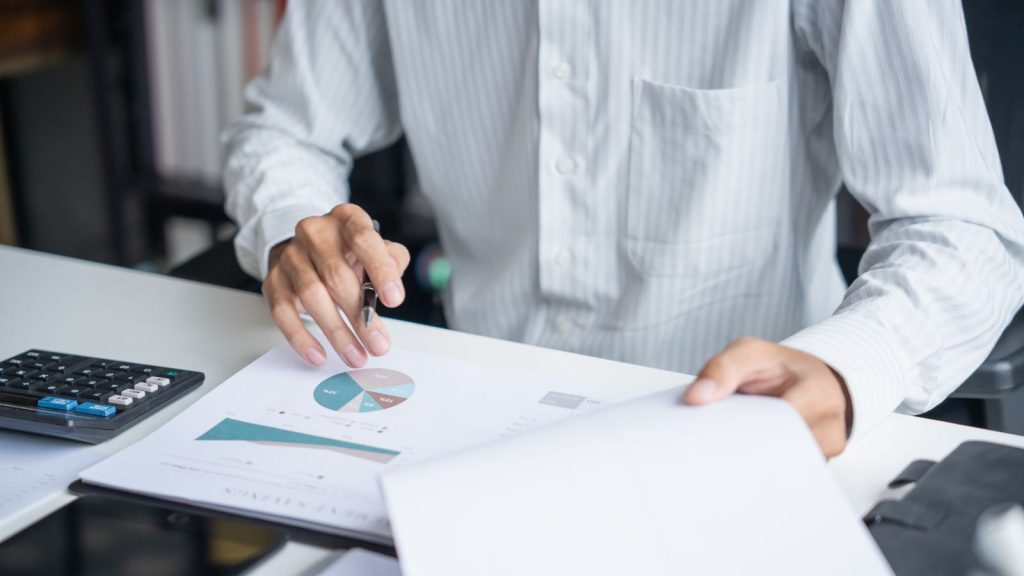 Contador revisando un informe financiero con gráfico circular y calculadora en su oficina
