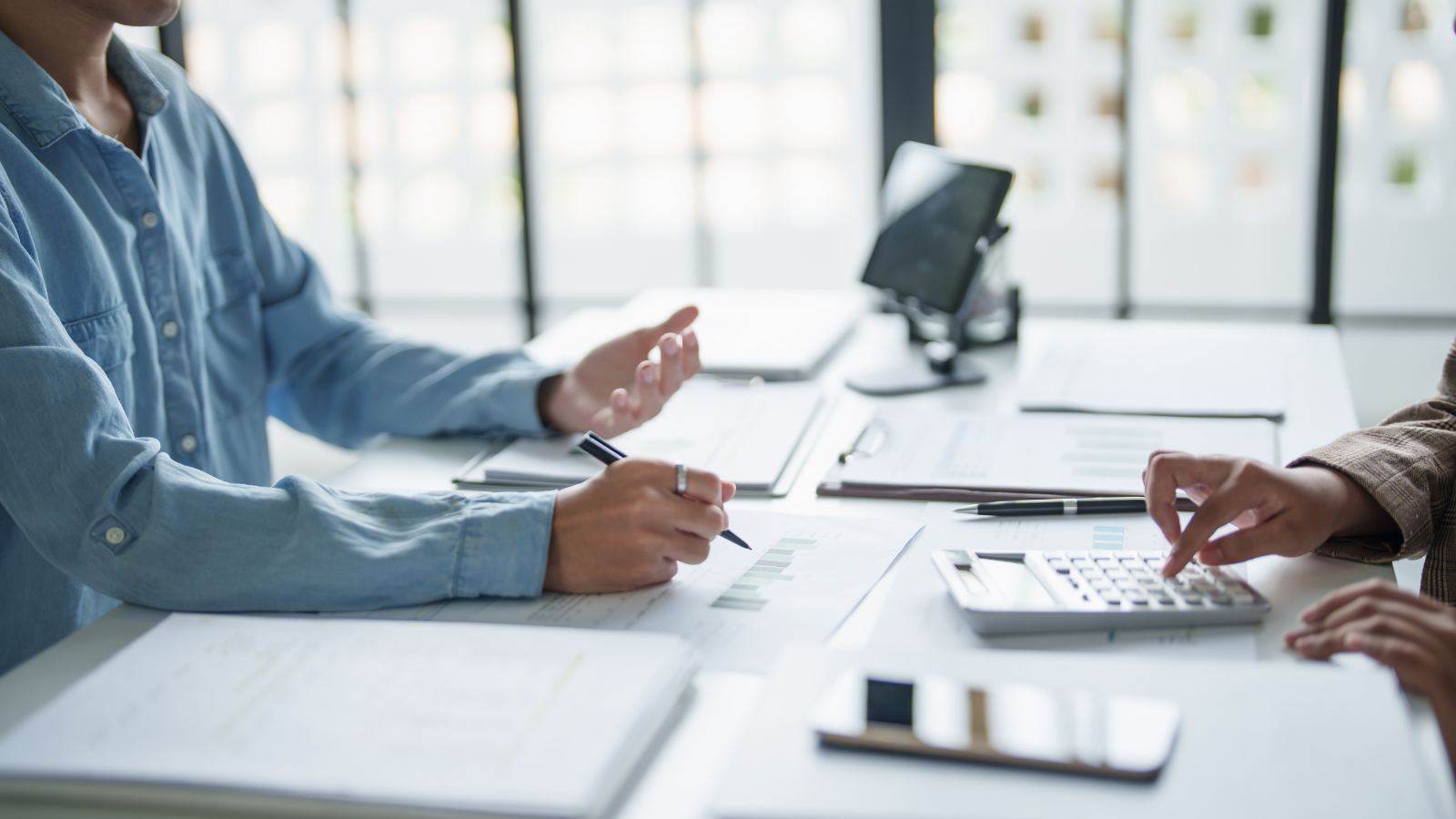 Asesor contable y cliente revisando obligaciones tributarias y cálculos de boletas de honorarios sobre una mesa de trabajo.