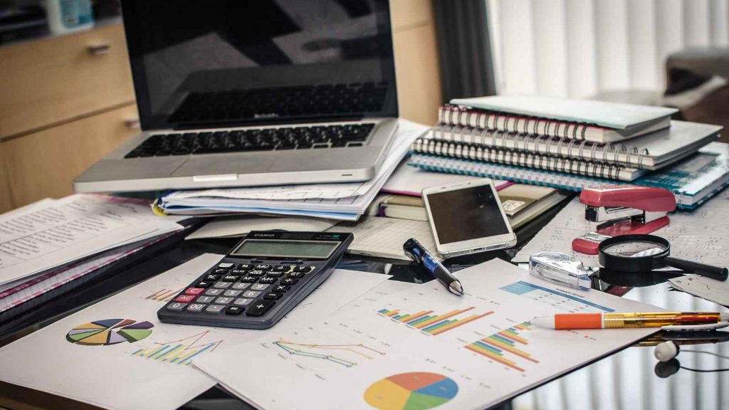Escritorio de un contador con laptop, calculadora y gráficos financieros para llevar los libros contables de una empresa