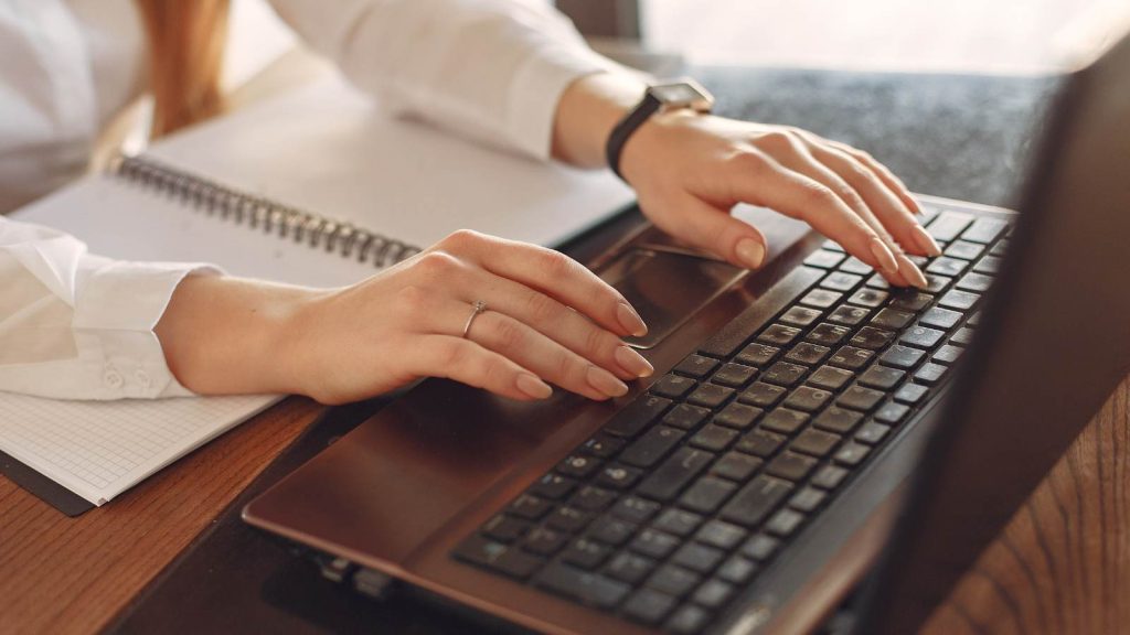 Manos escribiendo en el teclado de un laptop para rectificar la Declaración de Renta en el sitio del SII