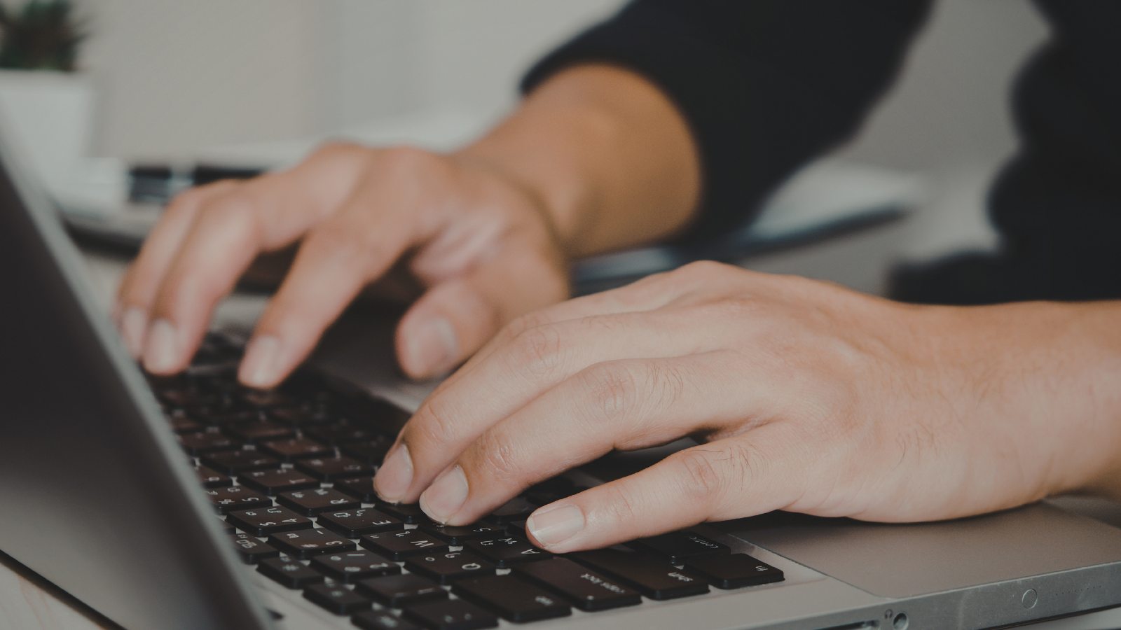 Persona escribiendo en el teclado de su laptop para gestionar en línea la rectificación de la Declaración de Renta