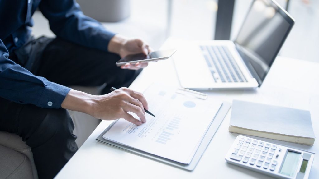 Hombre de negocios revisando un informe financiero con gráficos y calculadora para determinar los gastos deducibles de su empresa